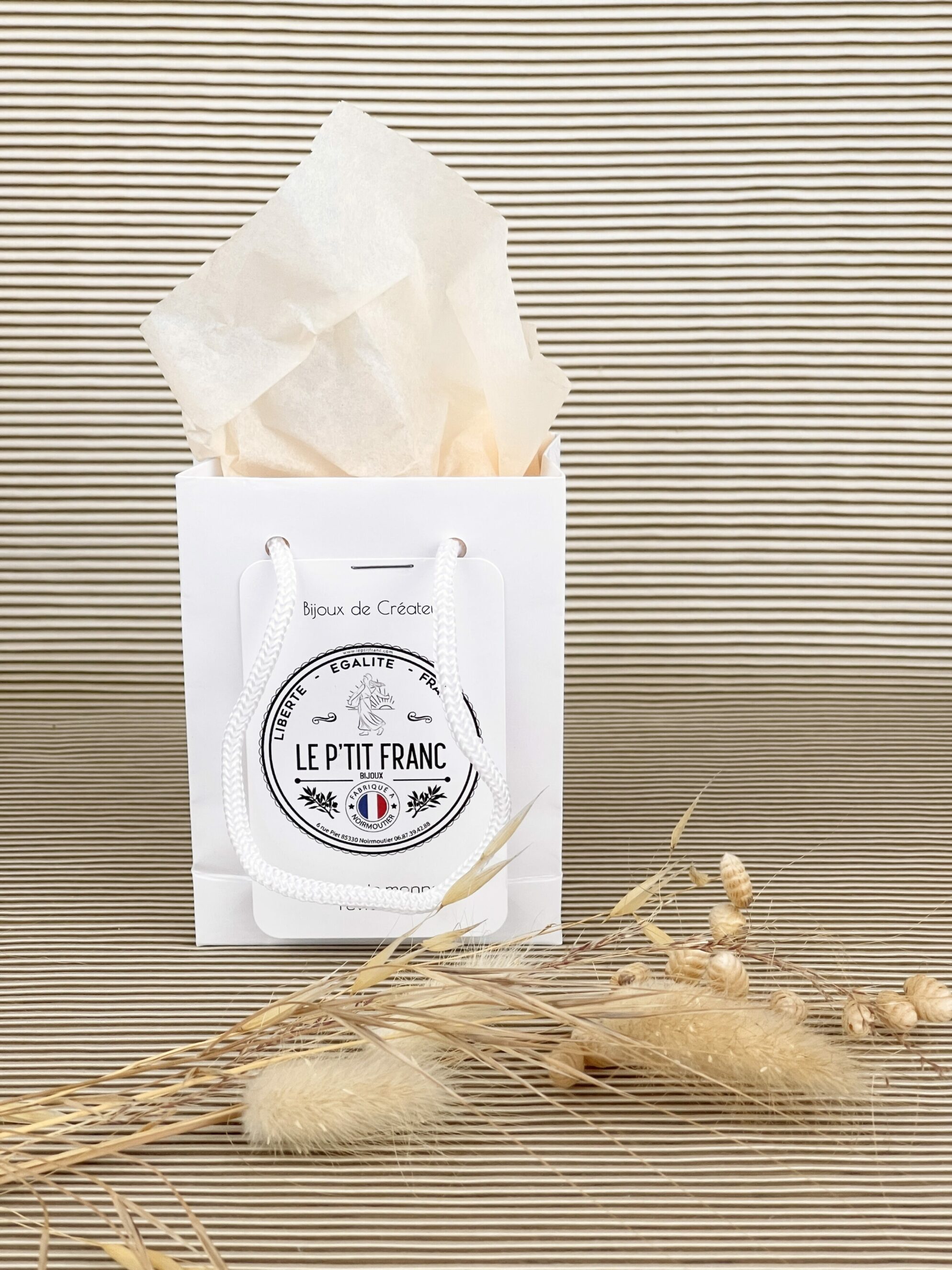 Emballage cadeau, petit sachet en coton floqué à la marque le P'tit Franc et paquet pelliculé brillant blanc avec cordelettes