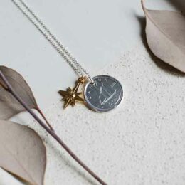 Collier réalisé à partir de la pièce de 10 cents canadien, on voit un bateau, la pièce est accompagnée d'une médaille étoile du nord plaquée or.