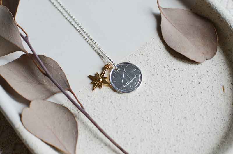 Collier réalisé à partir de la pièce de 10 cents canadien, on voit un bateau, la pièce est accompagnée d'une médaille étoile du nord plaquée or.